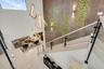 Two-story entrance featuring geometric pendant lighting, a skylight, a glass railing staircase, and a tiled accent wall with green moss-like inserts
