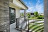 Outdoor balcony featuring a black metal horizontal slat railing, light-colored tile flooring, and a full-light glass door