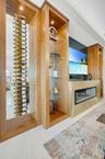 Integrated custom cabinetry featuring a wine storage display, glass shelving, and accent lighting
