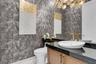 Powder room featuring a sleek vessel sink, gold-finish fixtures, and a black speckled countertop