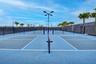 Multiple pickleball courts featuring blue and gray playing surfaces, white court lines, and black netting