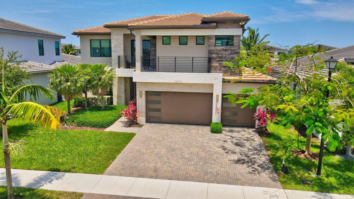 Contemporary two-story residence featuring a tile roof, a second-story balcony with dark railings, and a stone facade accent