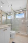 Bathroom featuring a glass-enclosed shower with subway tile surround, a single vanity with stone countertop, and a white toilet