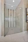 Glass-enclosed shower featuring a tiled floor and built-in shelving