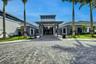 Contemporary building entrance featuring an extended portico, glass double doors, and a paver drive