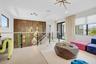Open-concept living space featuring light wood-finish flooring, a contemporary chandelier, and a decorative accent wall with geometric lighting fixtur