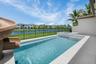 Resort-style pool with integrated spa and water slide, surrounded by light-toned patio pavers and offering a serene water feature backdrop