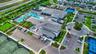 Expansive community clubhouse featuring a large swimming pool, multiple tennis courts, basketball court, and a circular drop-off area