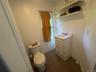 White vanity with an integrated sink and chrome faucet, accompanied by a toilet with a chrome flush lever