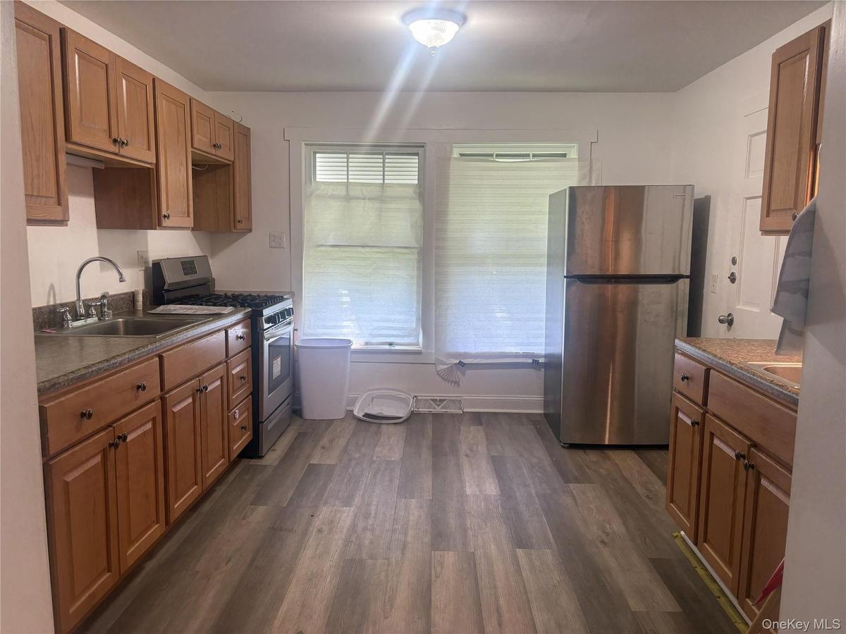 Kitchen featuring wood-finish flooring, wood cabinetry, a stainless steel refrigerator, and a stainless steel range