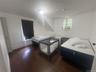 Hardwood flooring, painted interior door, window with white trim, additional window with white trim, white walls