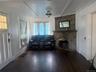 Stone-clad fireplace with a substantial mantel, dark wood-finish flooring, white paneled doors, and a decorative ceiling fixture