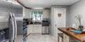 The first-floor kitchen features an open layout with bright marble-look flooring, crisp white cabinetry, and modern stainless steel appliances. A larg