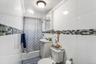 The first floor bathroom features bright white wall tiling accented by a stylish mosaic border that adds a modern touch. A compact pedestal sink and c