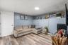 This spacious basement living room features beautiful wood-look flooring, cool blue walls, and a comfortable layout. It is a highly versatile space th