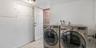 The spacious laundry room features a modern, side-by-side washer and dryer set with an efficient and clean white layout. The room offers plenty of spa