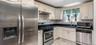 The first-floor kitchen features an open layout with bright marble-look flooring, crisp white cabinetry, and modern stainless steel appliances. A larg