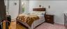 The spacious master bedroom features warm hardwood flooring, clean white walls, and a bright window that overlooks the property. The expansive layout 