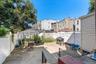 The spacious backyard is fully enclosed by a clean white privacy fence, offering a secure and low-maintenance outdoor retreat. It features a large pav