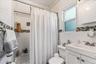 The second floor bathroom is clean and bright, featuring a white vanity, matching wall tiles, and a stylish mosaic border. A frosted window lets in gr