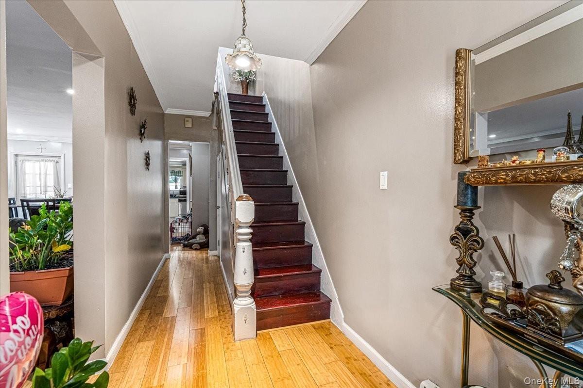 A striking dark wood staircase stands out as a beautiful centerpiece, perfectly complementing the bright hardwood floors. The long hallway draws you f