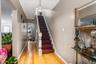 A striking dark wood staircase stands out as a beautiful centerpiece, perfectly complementing the bright hardwood floors. The long hallway draws you f
