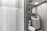 The bathroom is fully finished with modern grey wall tiling, a clean white vanity, and bright overhead lighting. This additional full bath includes a 