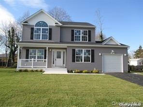 Traditional-style house featuring an attached garage, covered porch, driveway, and a front lawn