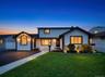 Modern-style exterior featuring a white facade with dark trim, an arched window, and multiple outdoor sconces