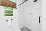 Glass-enclosed shower with a rainfall showerhead, tiled walls, and a built-in shower niche