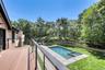 Expansive deck with cable railing, shingle siding, rectangular swimming pool, integrated spa, and tiered landscaping