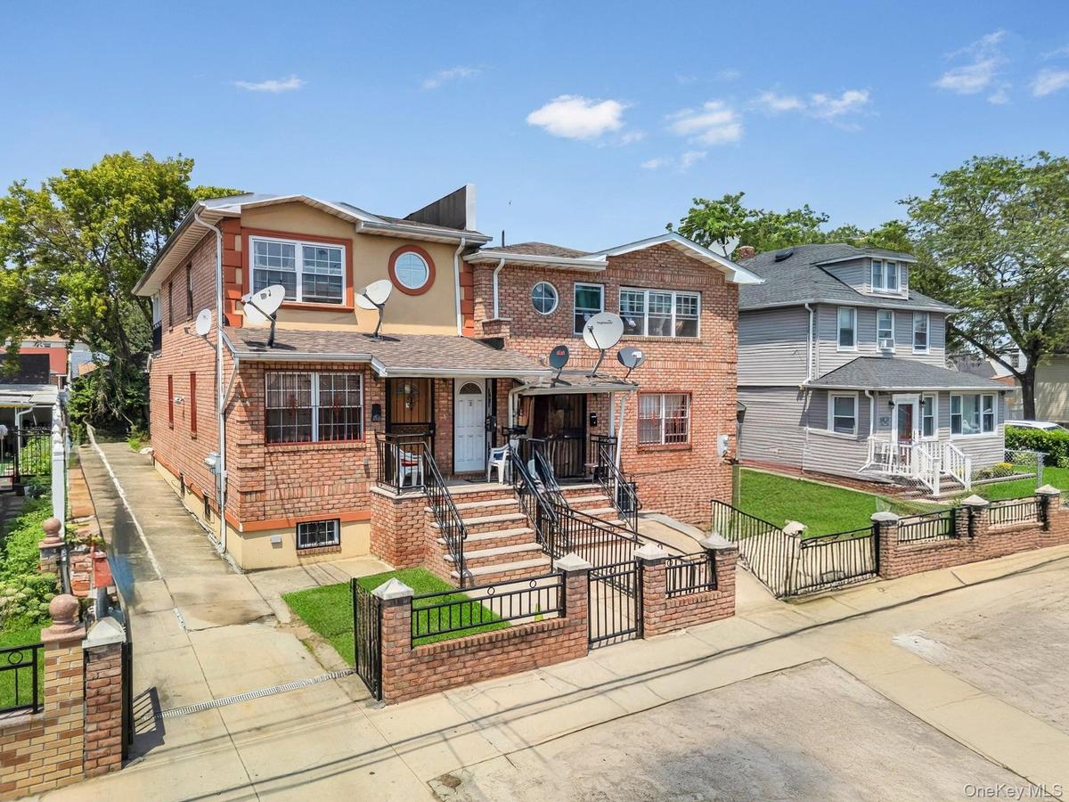 View of front facade featuring a gate, a fenced front yard, brick siding, and a porch