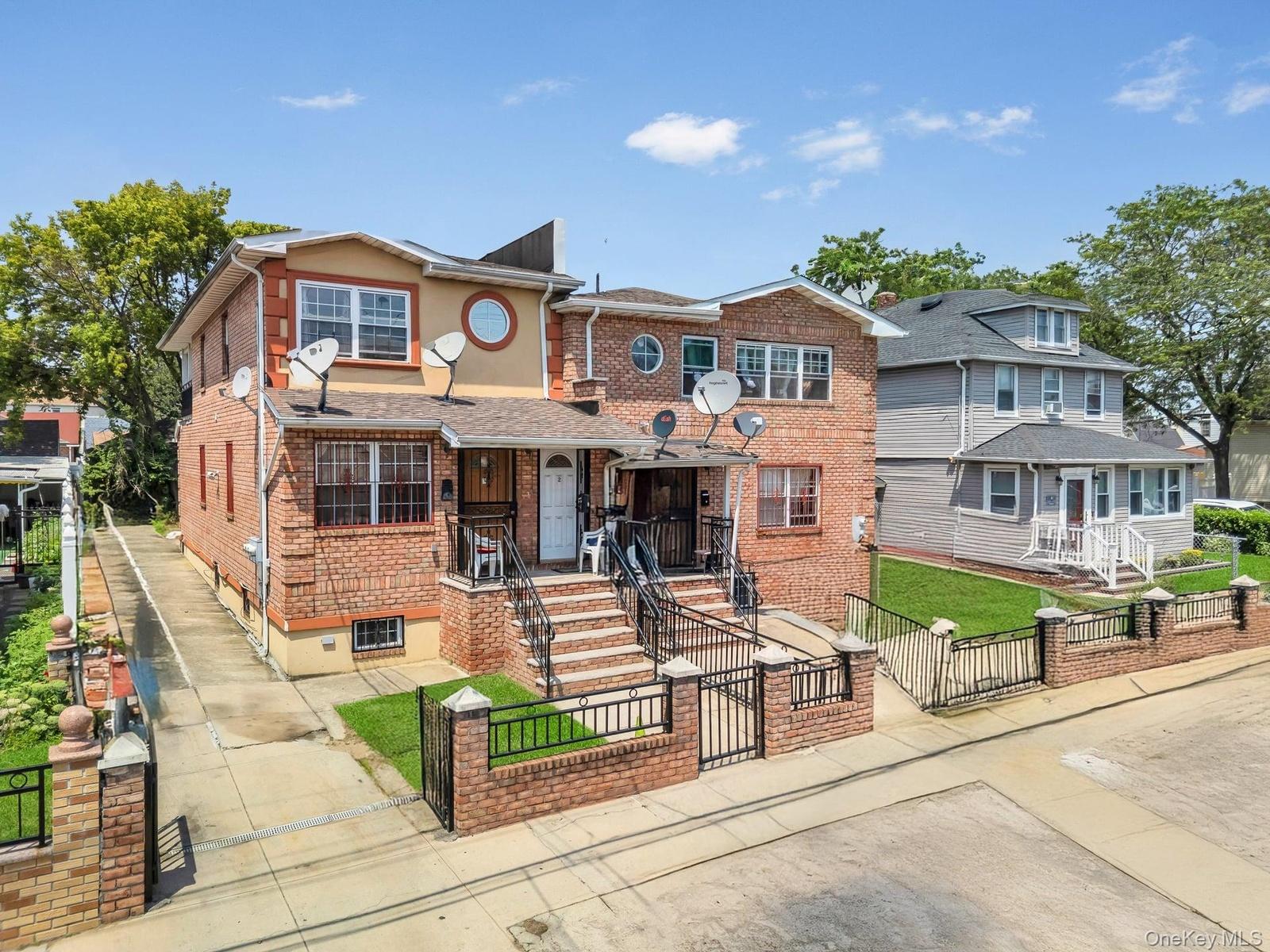View of front facade featuring a gate, a fenced front yard, brick siding, and a porch