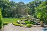 Koi pond with a three-level waterfall, full plumbing and filtration system, and a covered design complete with a dedicated viewing bench.