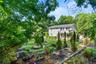 Three-tier terrace garden beds with layered shrubs and a charming park bench create a beautiful, structured outdoor retreat.