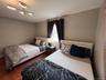 Third bedroom with two full size-beds and wood-finish flooring with neutral wall paint and a modern ceiling light fixture
