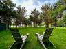 Large, leveled, and fenced backyard with mature trees offering shade and plenty space for play.