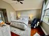 Primary room features vaulted ceiling, ceiling fan with integrated lighting, wood-finish flooring, and an arched window and a massage chair