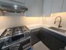 Stainless steel range with a coordinating range hood, undermount sink with a matte black faucet, integrated dishwasher, and under-cabinet lighting