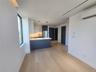 Wood-finish flooring throughout, complemented by a modern kitchen featuring white and dark blue cabinetry, integrated appliances, and pendant lighting
