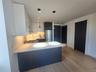 Modern kitchen featuring light-toned wood-finish flooring, white and gray cabinetry, a gas cooktop, and stainless steel appliances