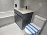 Bathroom featuring a white soaking tub, vanity with a rectangular basin, black faucet, and tiled walls