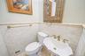 White subway tile wainscoting, pedestal sink with brass-finish fixtures, and decorative mirror