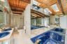 Wood-beamed vaulted ceiling with skylights, mirrored walls, dual integrated deep blue sinks, a walk-in shower with glass enclosure, and a built-in jet
