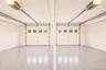 Two garage bays featuring white overhead doors with window inserts and automatic openers