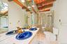 Dual vanity with blue vessel sinks and gold-tone fixtures, glass-enclosed shower, exposed wood beam ceiling, and skylight