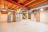 Unfinished basement with exposed ceiling joists, concrete flooring, and solid wood interior doors