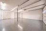 Epoxy-coated flooring, white walls, overhead fluorescent lighting, two panel doors, and a roll-up garage door with windows