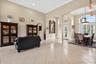 Arched doorways with crown molding, high ceilings, large windows with plantation shutters, and light-colored tile flooring
