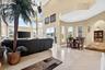 Vaulted ceiling with a ceiling fan, wall of windows with plantation shutters, tile flooring, built-in kitchen island with stone countertop, and arched
